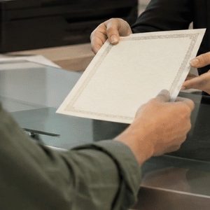 Pessoa recebendo uma certidão em um cartório, em um ambiente profissional e acolhedor, com atendimento presencial e clima de confiança.