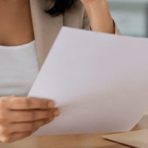 Pessoa concentrada analisa um documento em um escritório moderno, com expressão de preocupação e ambiente profissional iluminado naturalmente.